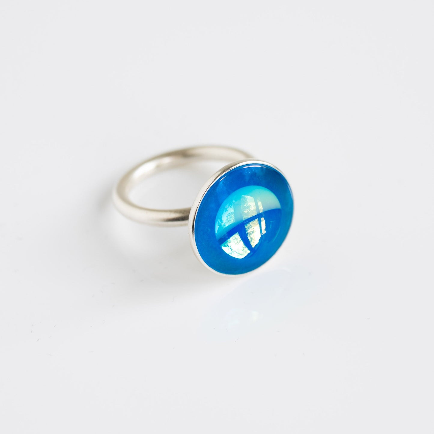 Silver ring with a blue circular gemstone on a white background