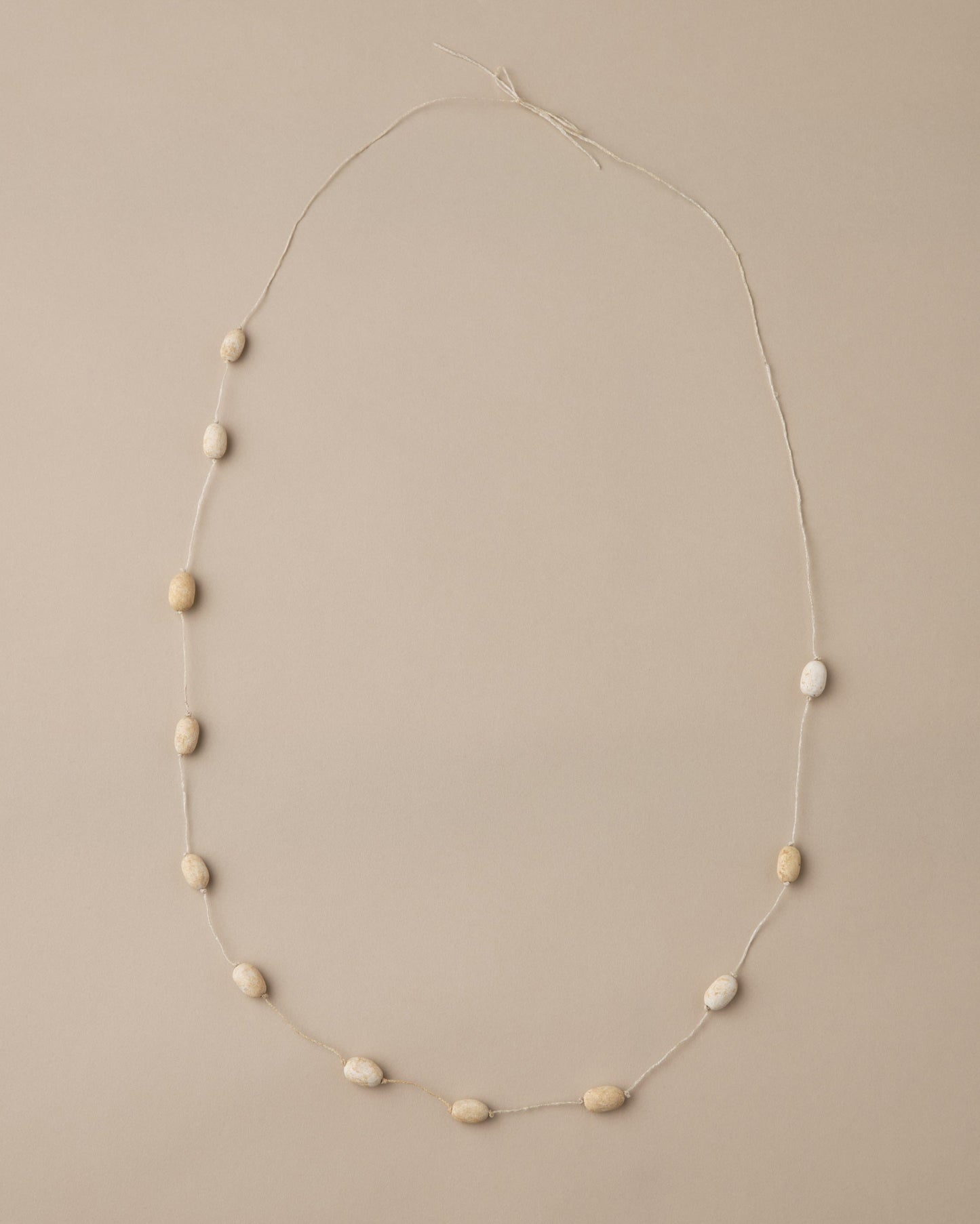 Necklace with small beige beads on a beige background