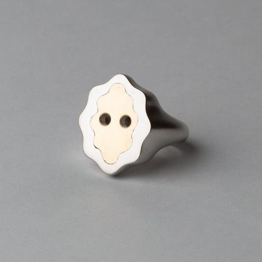 Silver ring with a white face design on a gray background