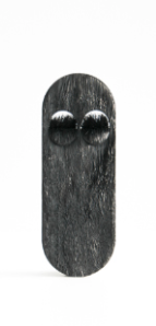 A long, black, fur-like brooch with eyes, made from saddle leather and animal hide, mounted on a steel rare earth magnet.