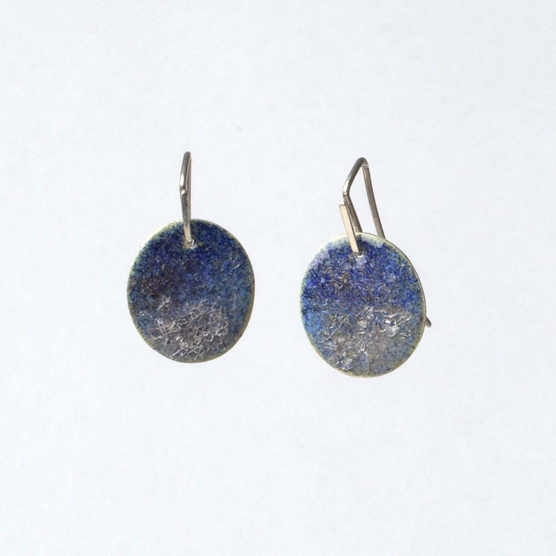Pair of round earrings with blue and silver disc design on a white background