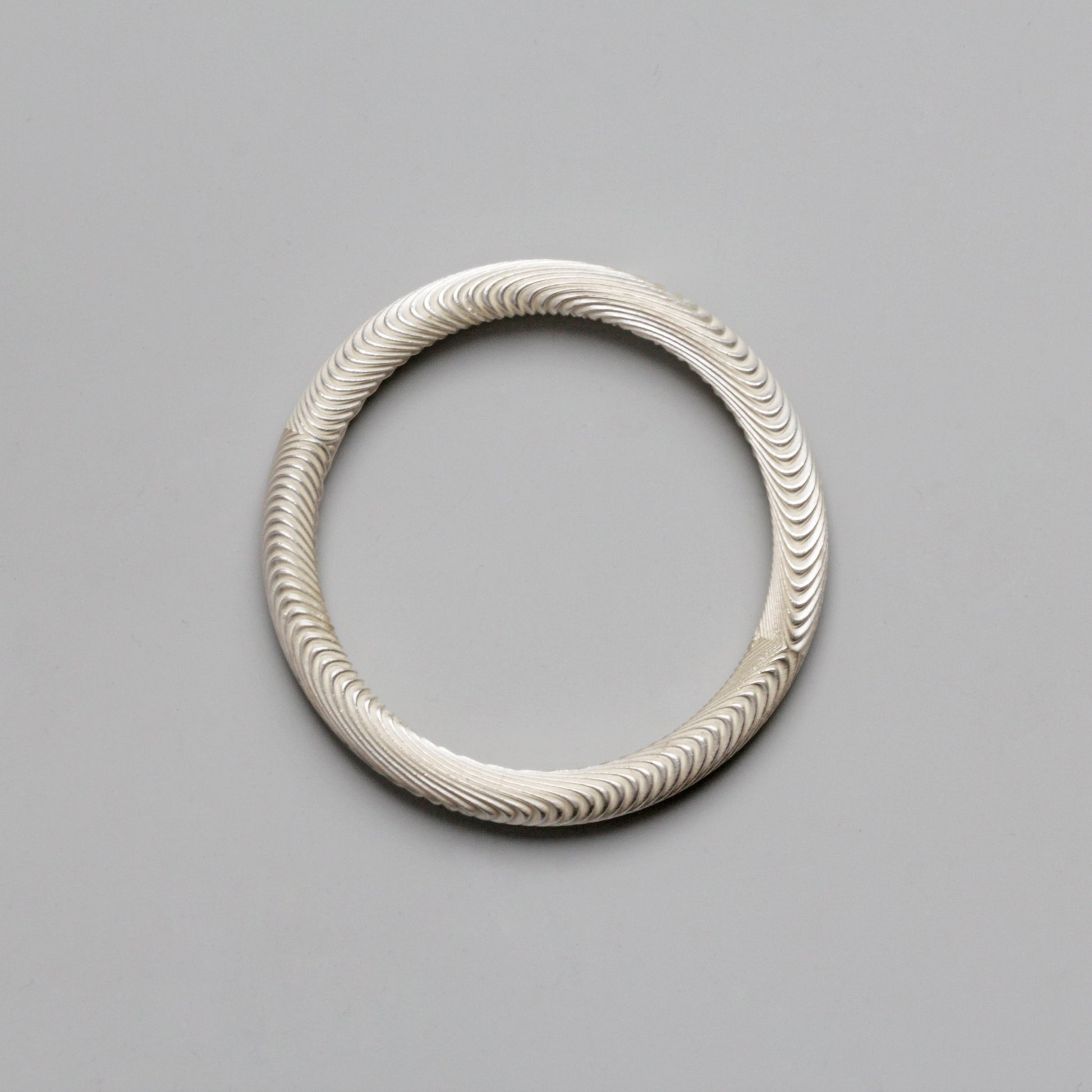 Silver bracelet with wavy pattern on a gray background