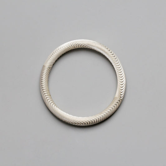 Silver bracelet with wavy pattern on a gray background