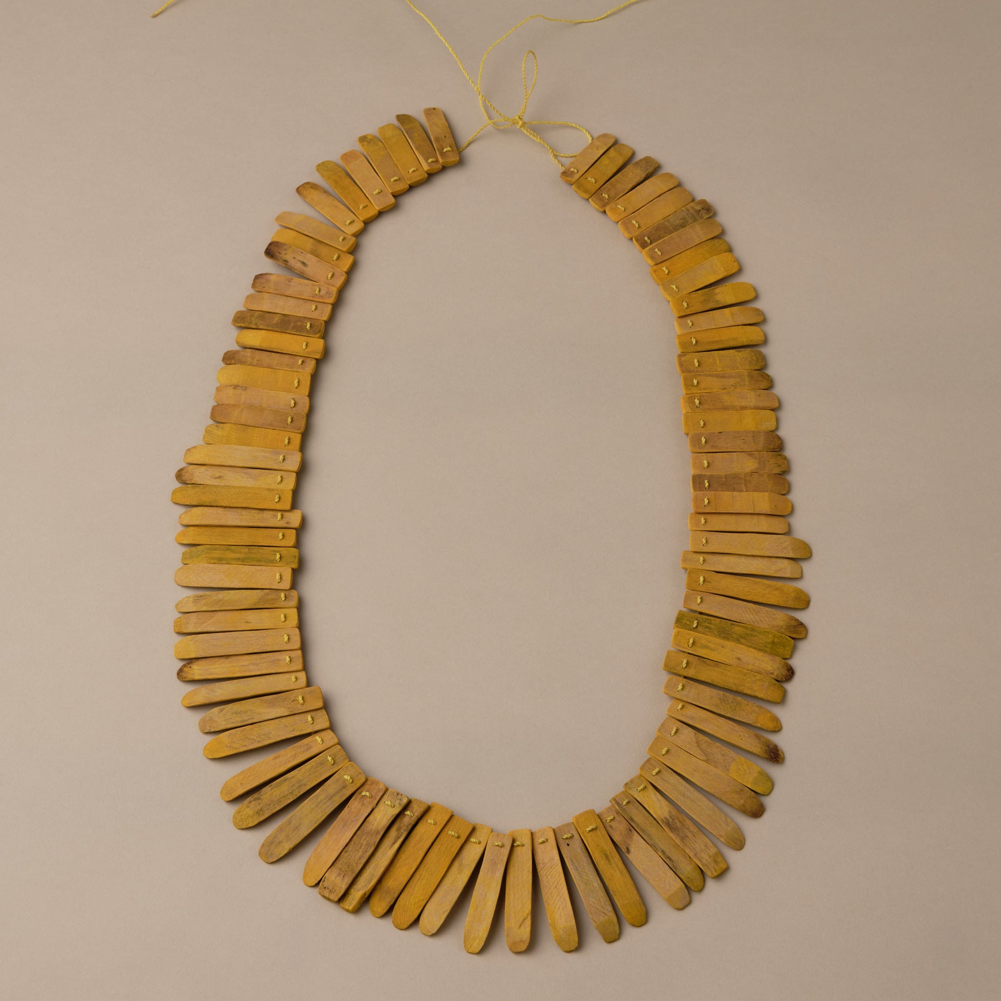 Necklace made of yellow wooden beads on a beige background