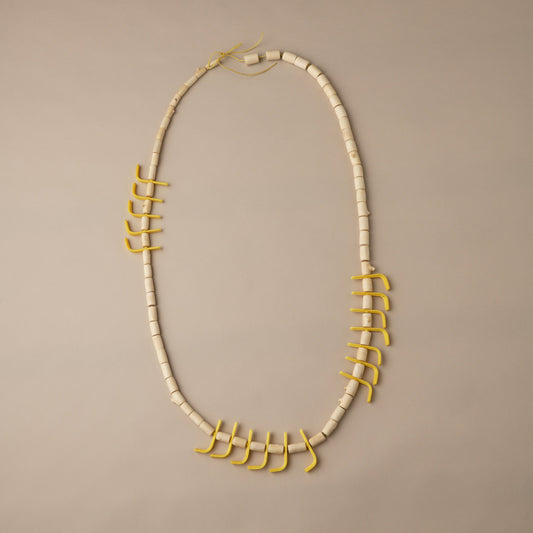 Necklace with white beads and gold accents on a beige background