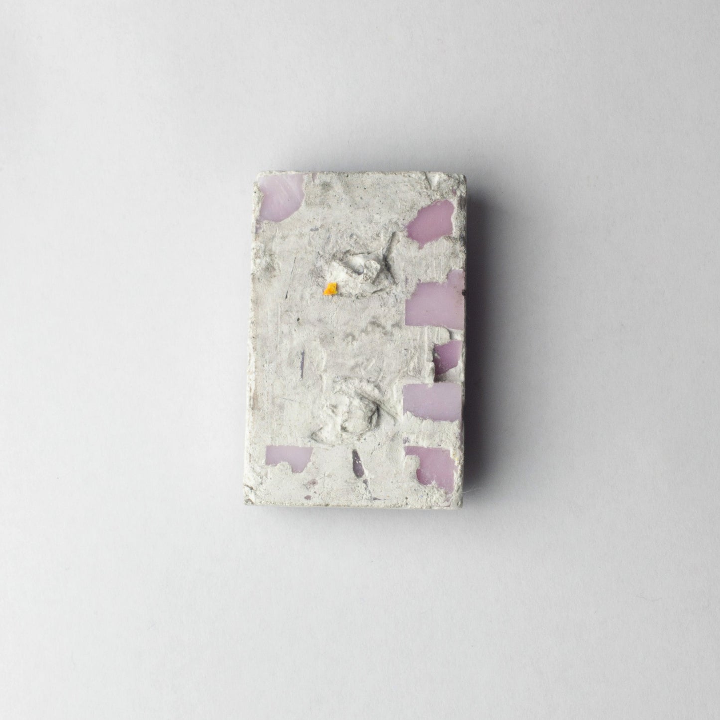 A rectangular concrete block with embedded pink and purple stone chips, centered on a light gray background.