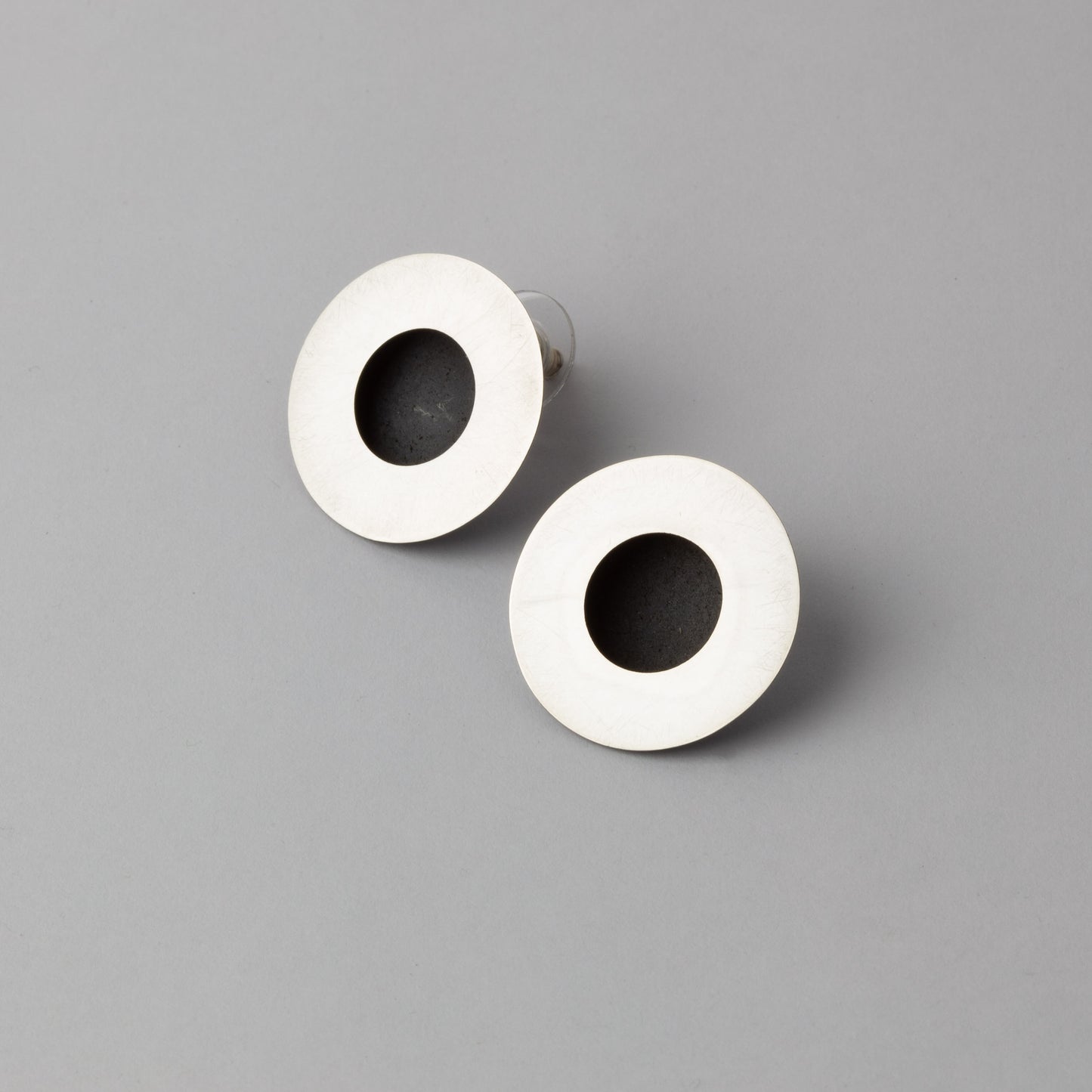 Pair of earrings with white circular design and black center on a gray background