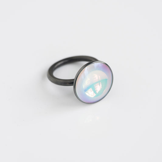 Ring with a round, iridescent gemstone on a light gray background
