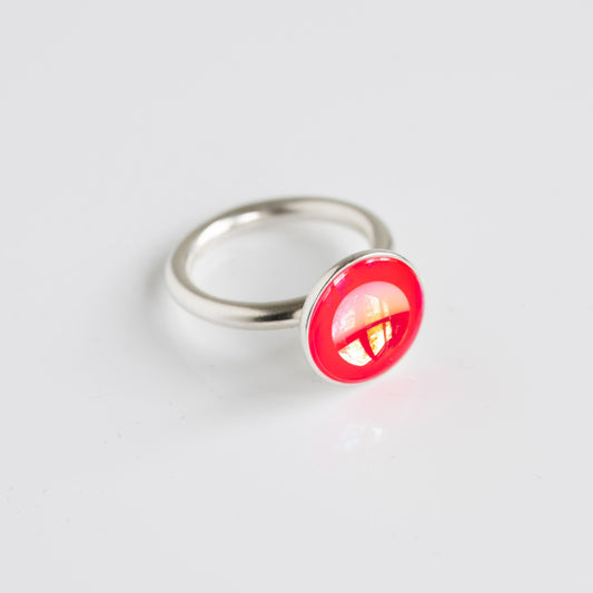 Silver ring with a red gemstone on a light gray background