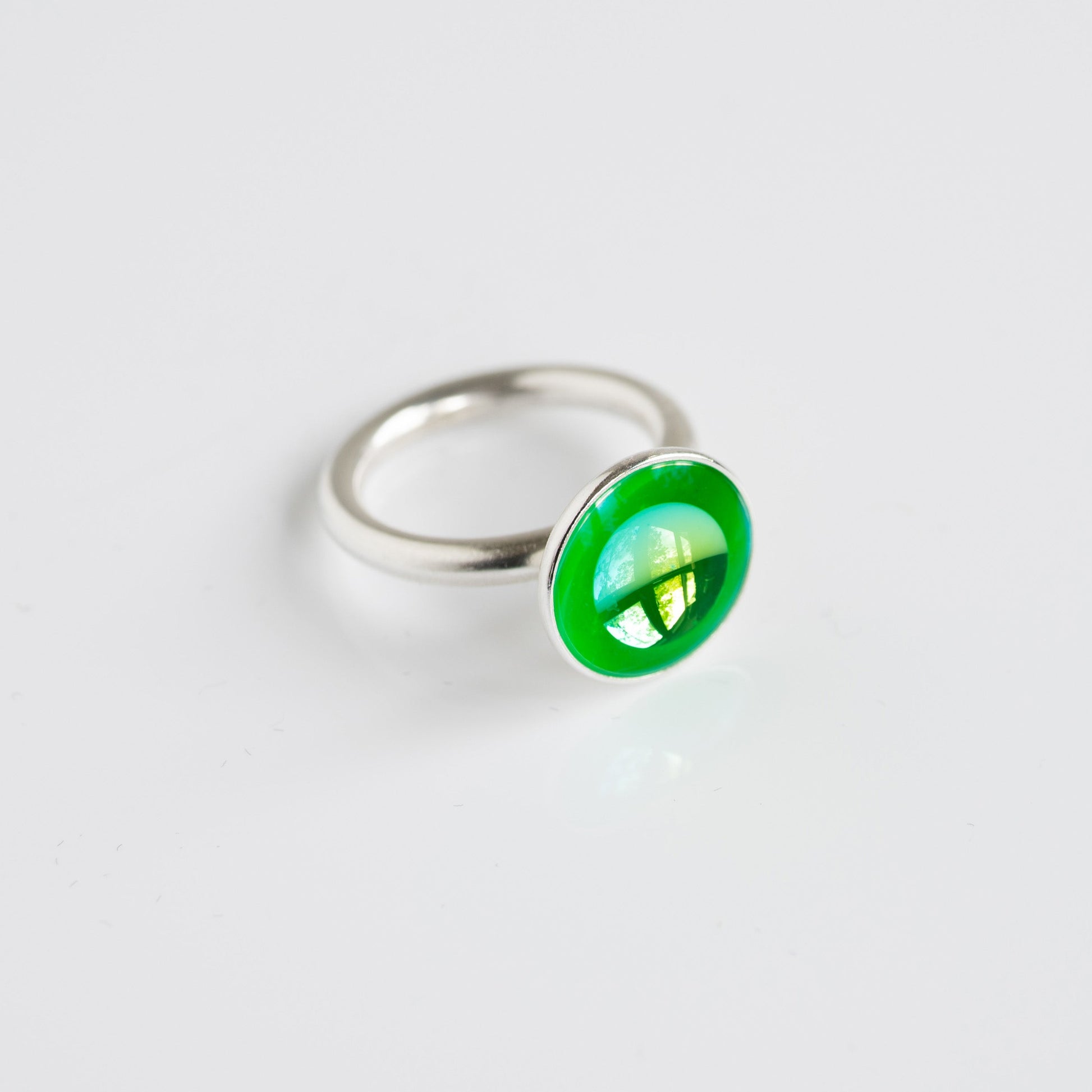 Silver ring with a green gemstone on a white background