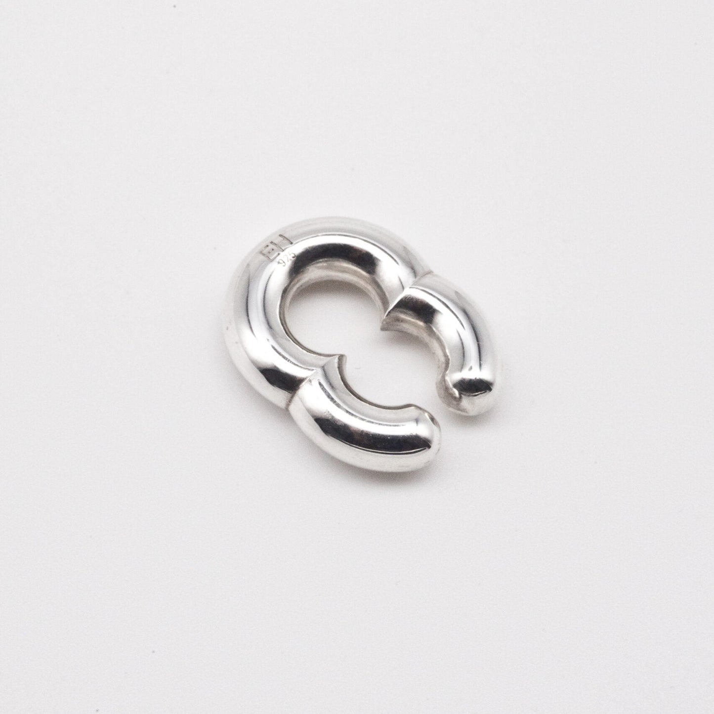 Silver earring on a light gray background