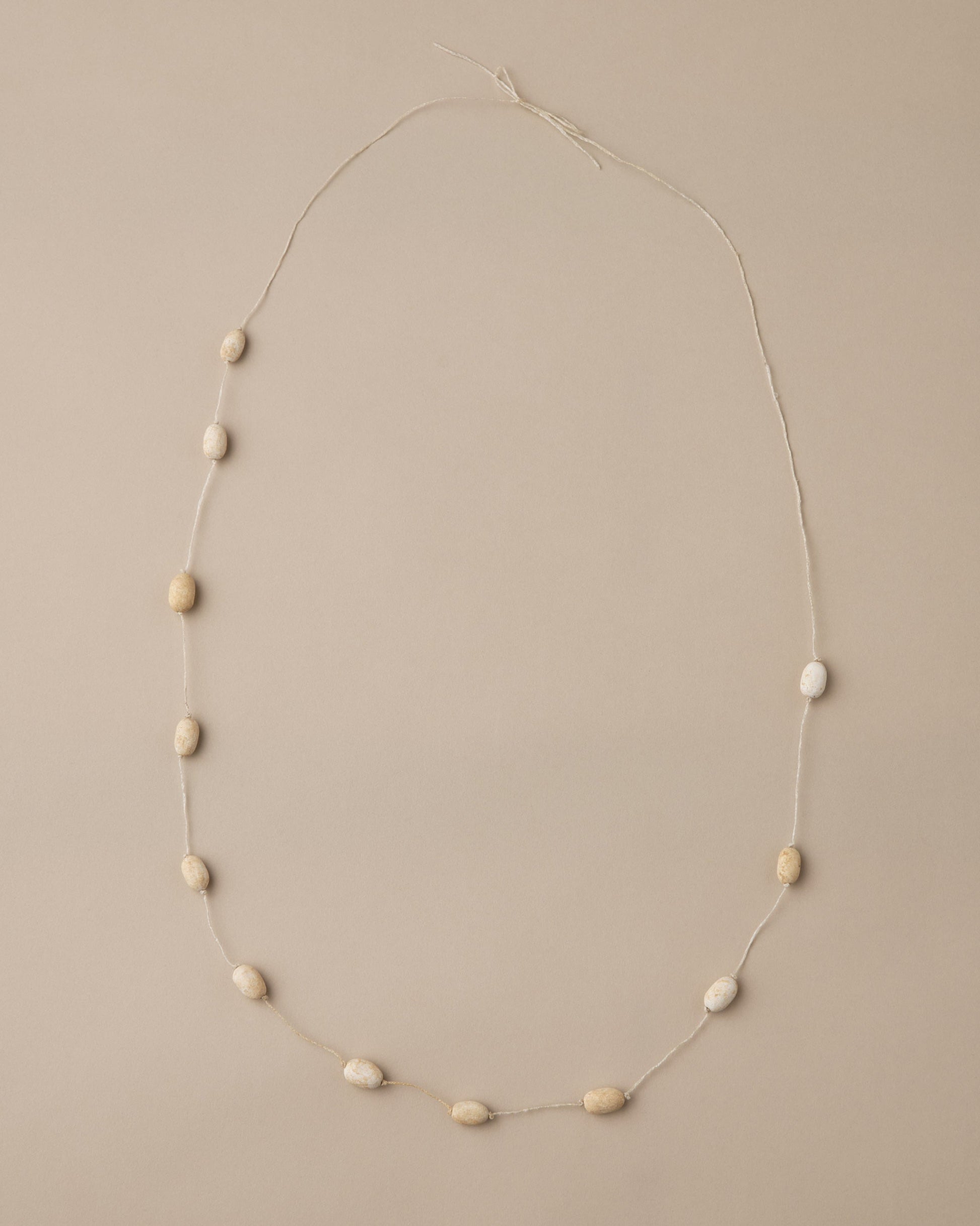 Necklace with small beige beads on a beige background