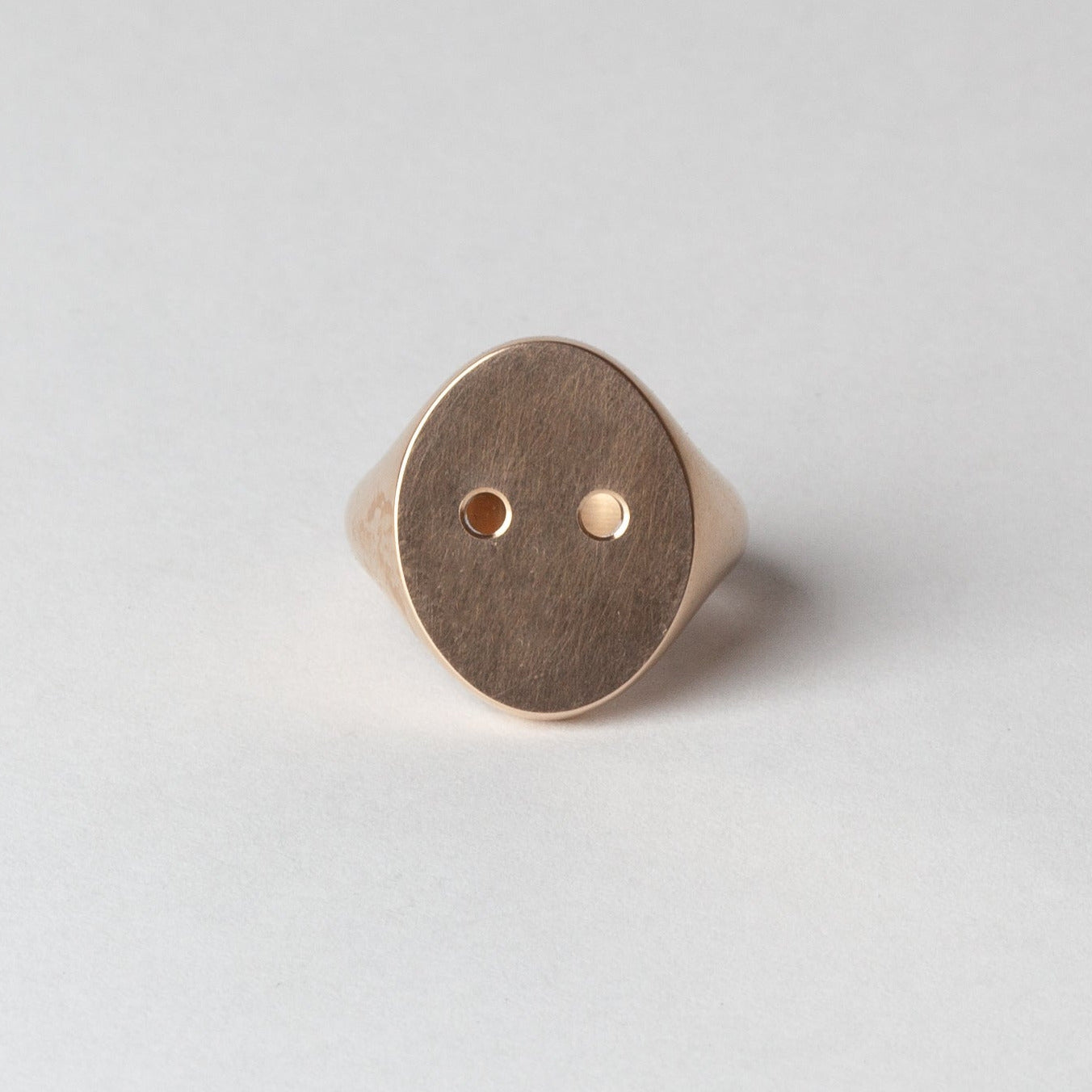 Gold ring with a circular design on a light gray background