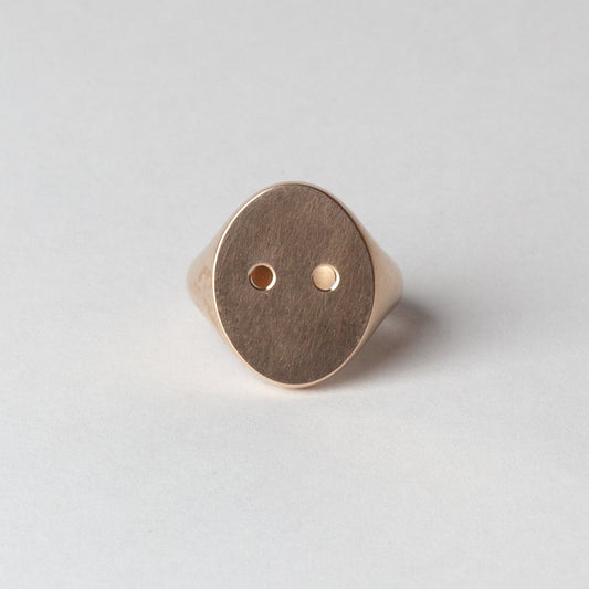 Gold ring with a circular design on a light gray background