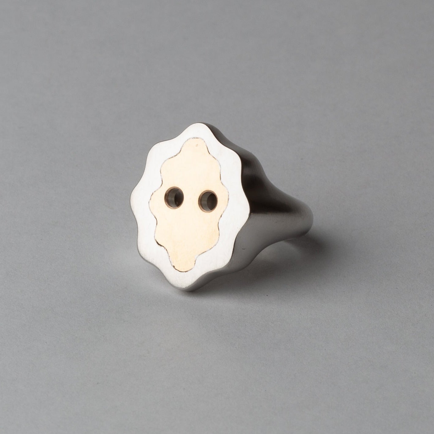 Silver ring with a white face design on a gray background