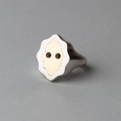 Silver ring with a white face design on a gray background