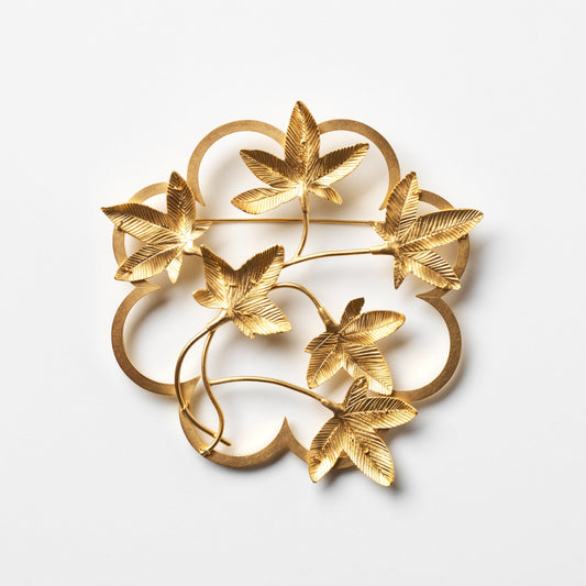 Gold leaf-shaped brooch on a white background