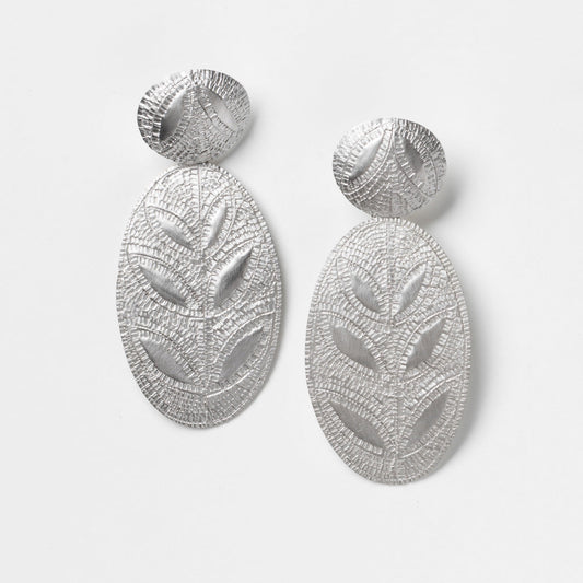 Pair of silver leaf-patterned earrings on a light gray background