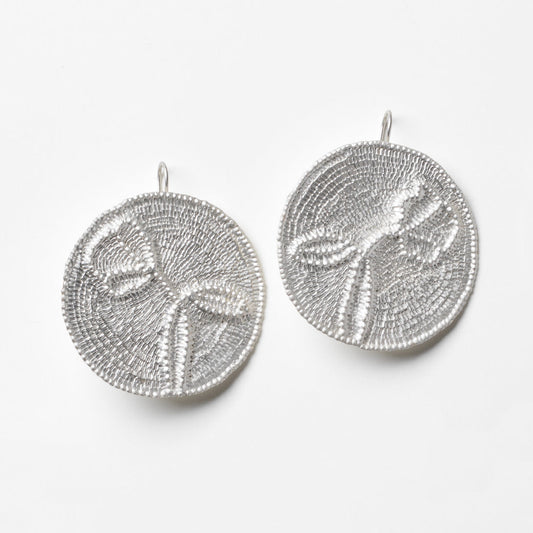 Pair of silver textured round earrings on a white background