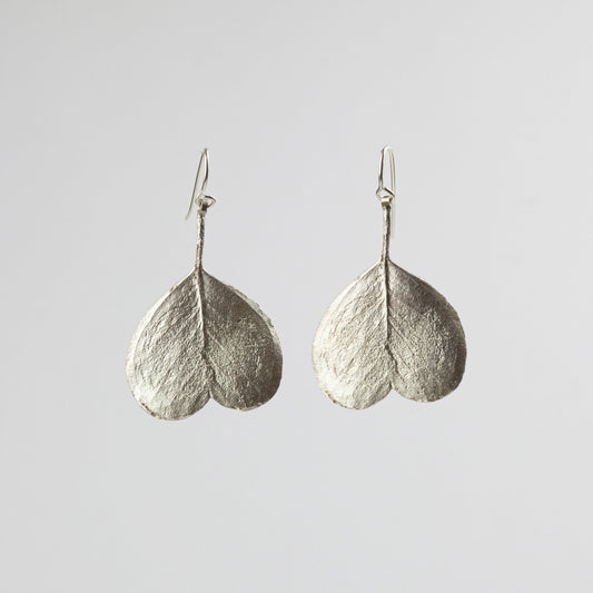 Pair of silver leaf-shaped earrings on a light gray background