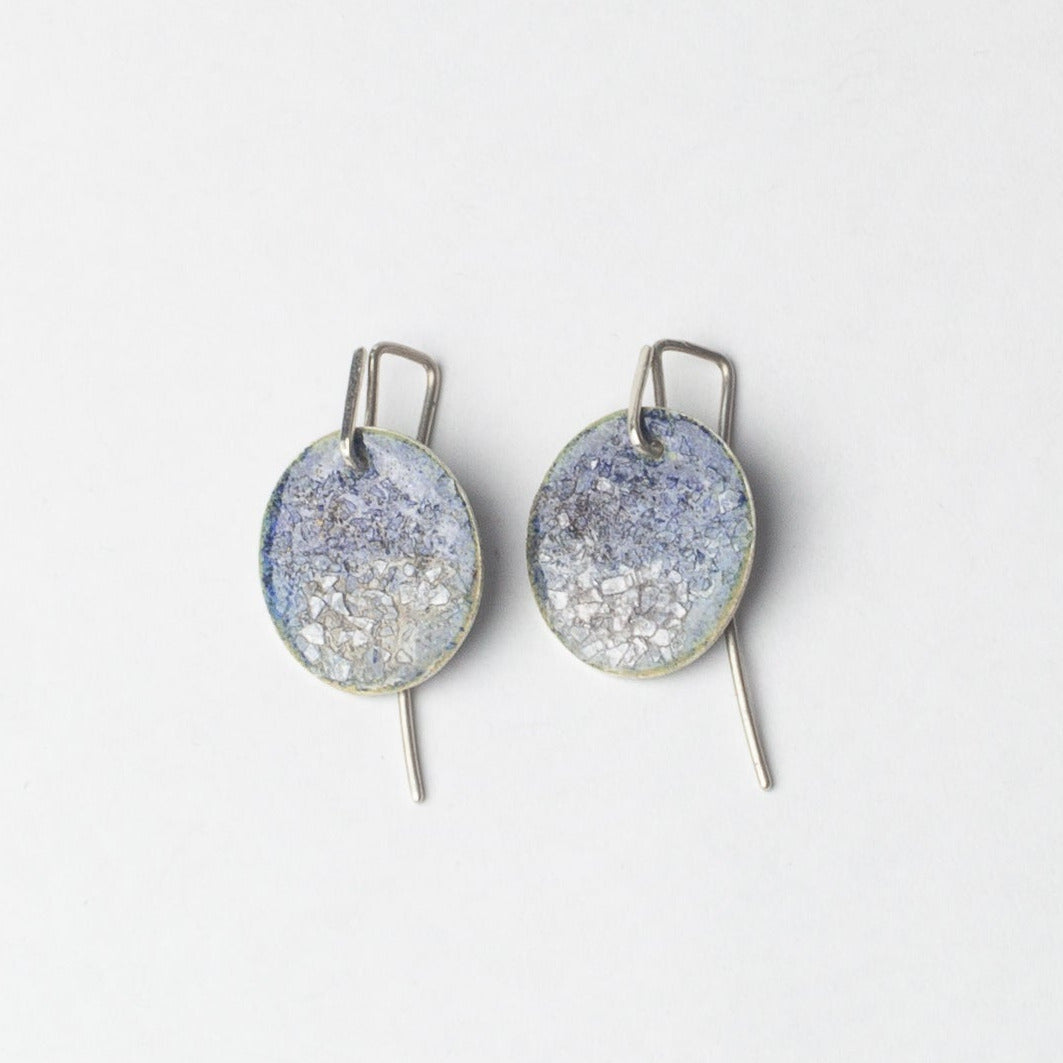 Pair of circular blue sparkly earrings on a white background