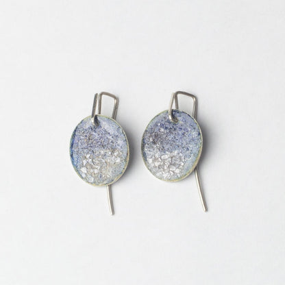 Pair of circular blue sparkly earrings on a white background