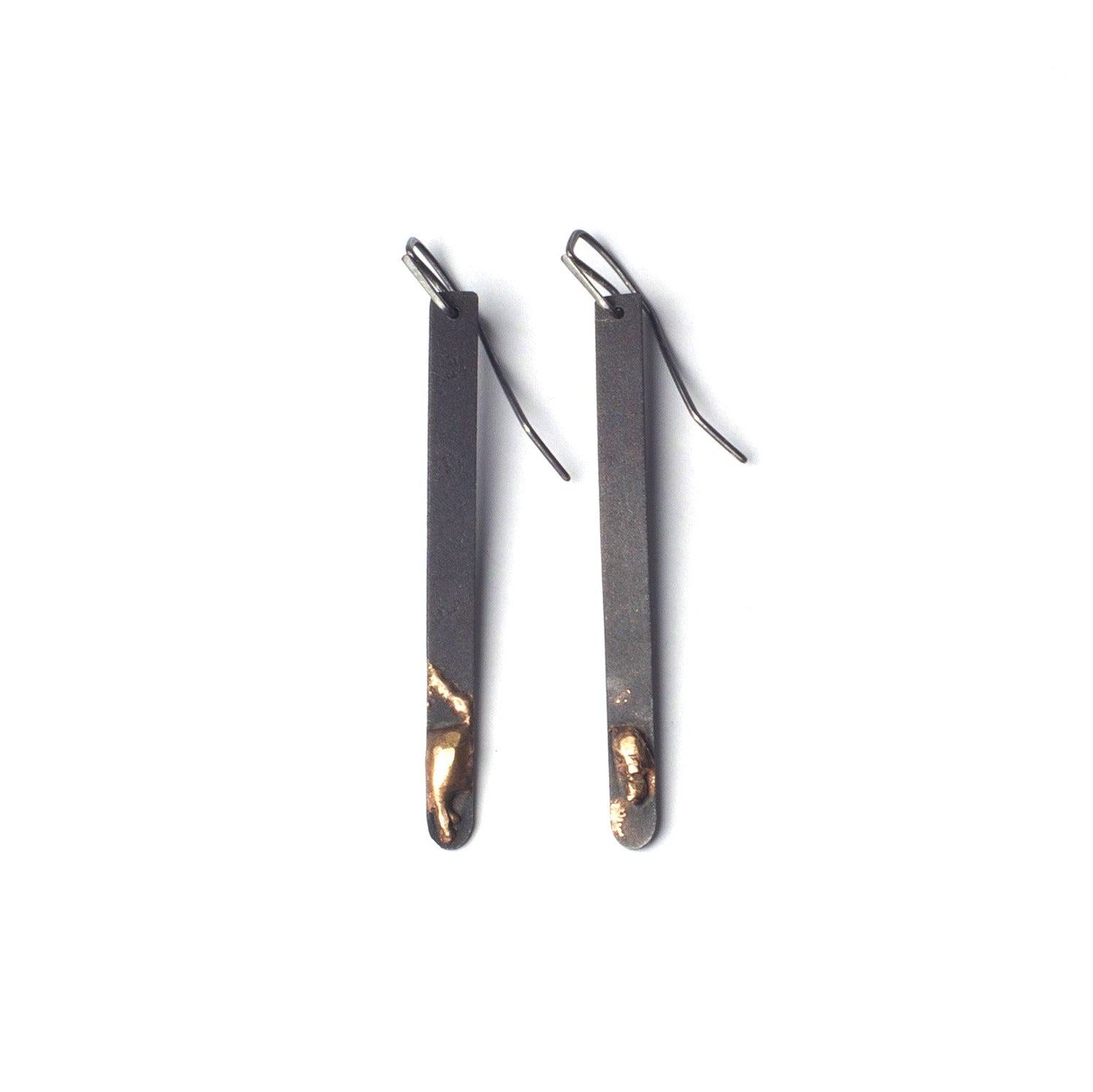 Pair of black earrings with gold accents on a white background