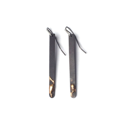 Pair of black earrings with gold accents on a white background