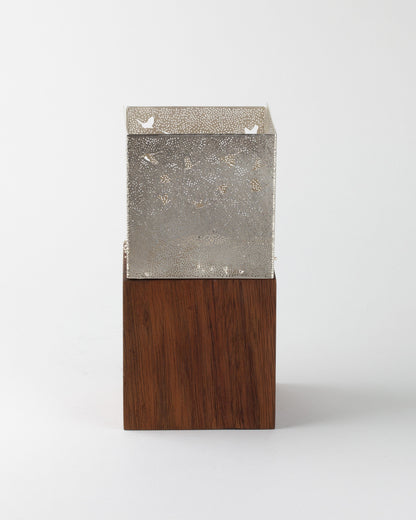 Two-tiered object with metallic top and wooden bottom on a white background