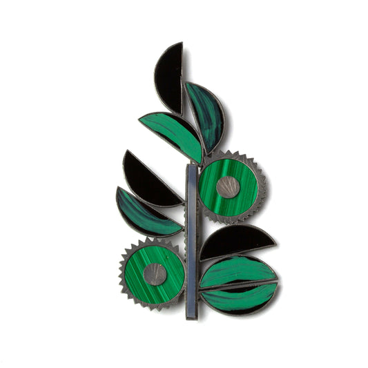 Decorative brooch with green and black leaf design on a white background